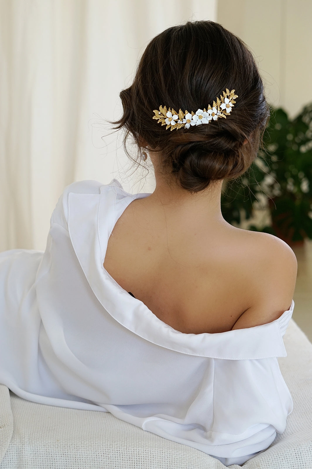 Mulher com cabelo apanhado e toucado dourado e flores brancas